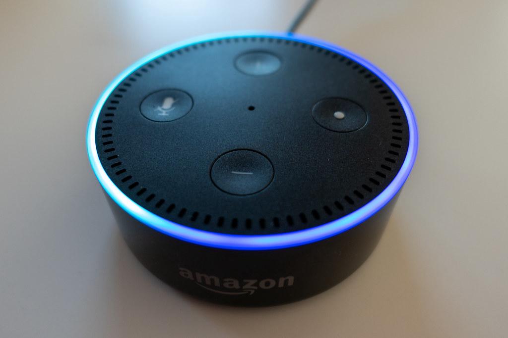 Ein Amazon Echo Gerät mit leuchtendem Alexa-Ring, das in einem Wohnzimmer steht.