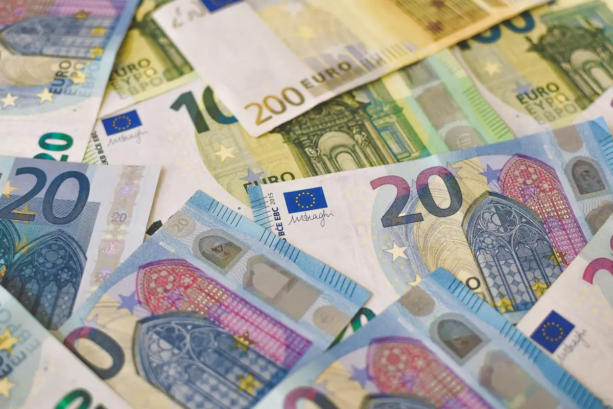 Nahaufnahme von Euro-Banknoten und -Münzen, die die finanzielle Stabilität der Währung symbolisieren, die durch Angela Merkels Führung gesichert wurde.